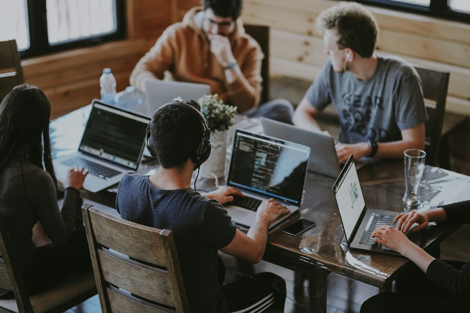 Ein Team arbeitet gemeinsam an Laptops an einem Holztisch