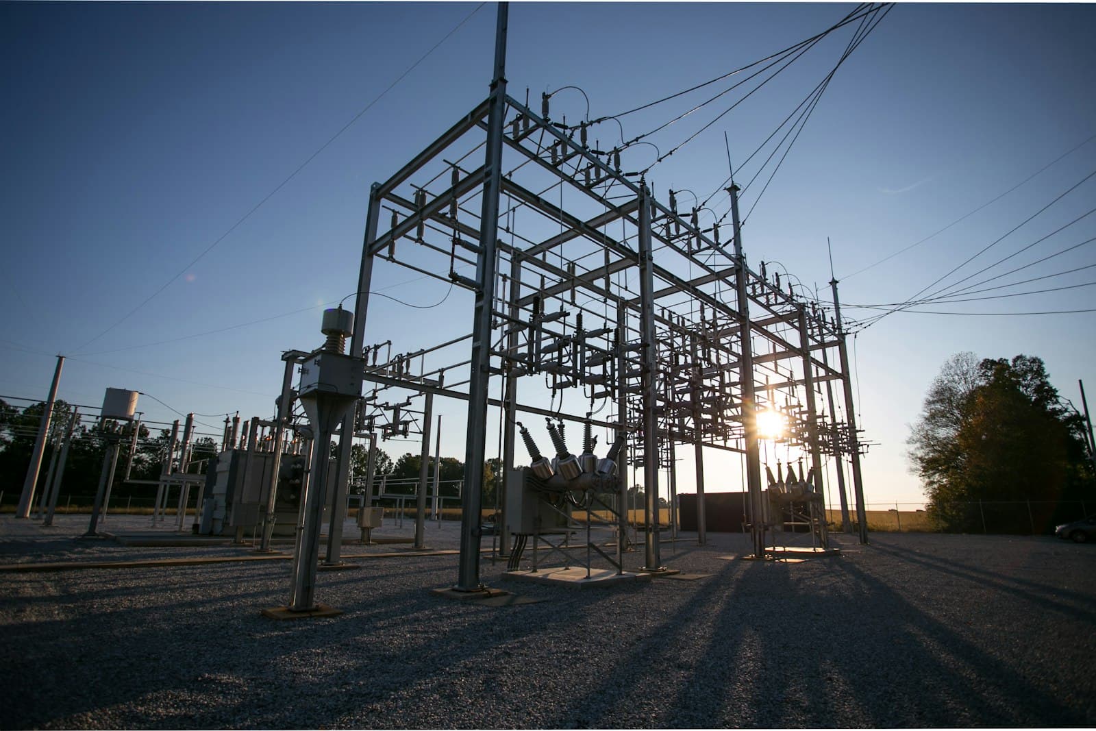 Umspannwerk mit Stahlgittermasten und Freileitungen im Gegenlicht der tief stehenden Sonne